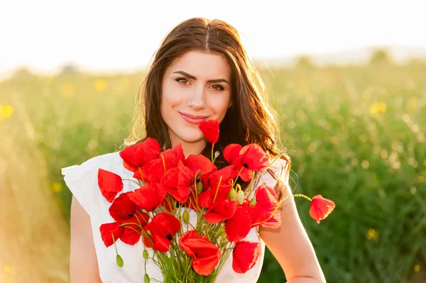 Krásná dívka přes nebe a slunce v oblasti držení kytice mák a s úsměvem — Stock fotografie