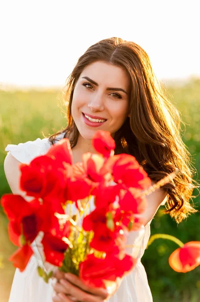 Jong mooi meisje in het veld met een papaver boeket. — Stockfoto