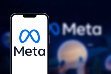  Smartphone with Meta or MetaVerse logo lies on wooden table with two paper Facebook logos.   Los Angeles, California, USA - 21 Jule 2022    