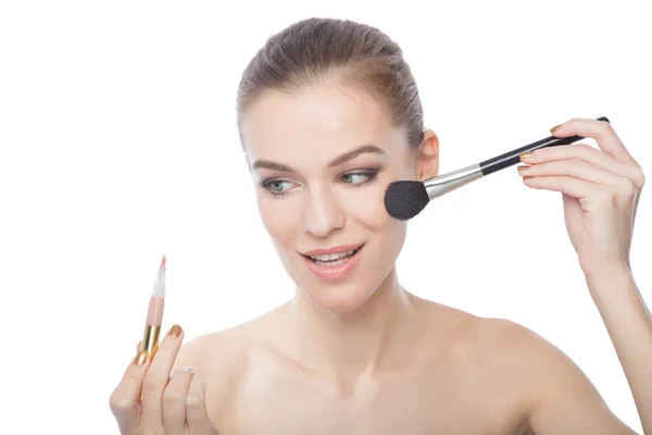 Modellen gör hennes makeup, isolerad på en vit bakgrund Stockbild