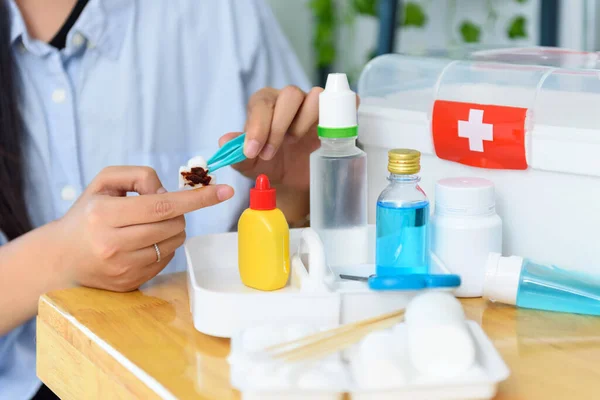 Kadın, evdeki ilk yardım çantasıyla parmağındaki yaraya antiseptik solüsyonu uyguluyor.