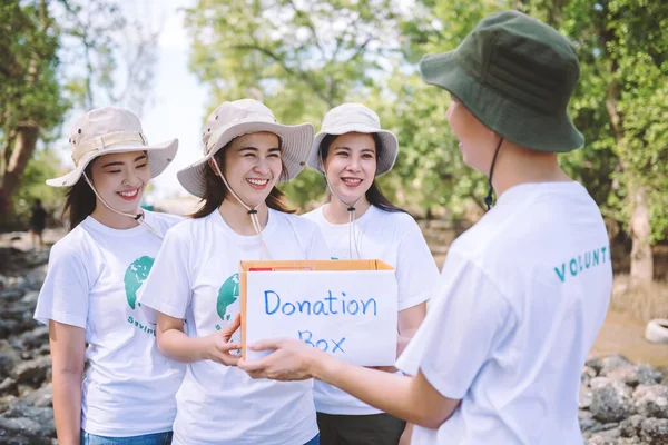 Group of asian diverse people volunteer holding a donation box for fundraiser to emergency situation such as help Ukraine, flood victims, food for children, charity event.Volunteering conceptual.