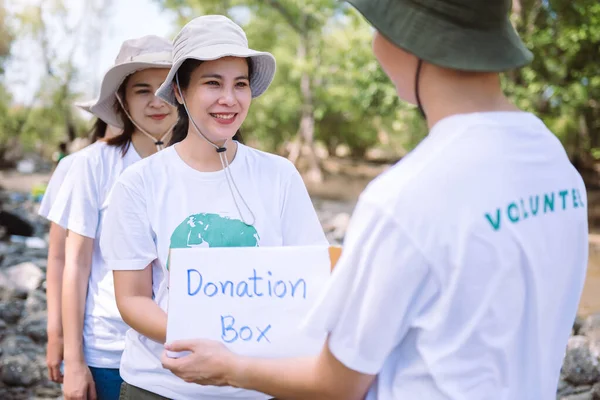 Group of asian diverse people volunteer holding a donation box for fundraiser to emergency situation such as help Ukraine, flood victims, food for children, charity event.Volunteering conceptual.