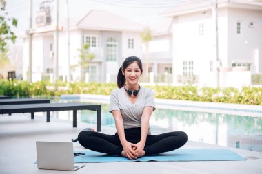 Mutlu Asyalı kadın, sabahları evde egzersiz ve yoga yapıyor. 