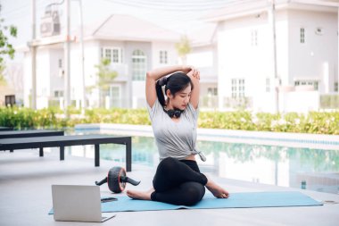 Mutlu Asyalı kadın, sabahları evde egzersiz ve yoga yapıyor. 