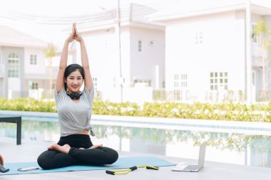 Mutlu Asyalı kadın, sabahları evde egzersiz ve yoga yapıyor. 