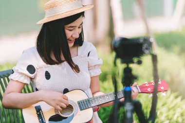 Parkta gitar çalan Asyalı kadın etkiler içerik, yaşam tarzı ve dinlenme konsepti oluşturmak için.