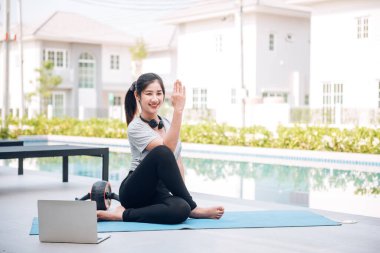Mutlu Asyalı kadın, sabahları evde egzersiz ve yoga yapıyor.