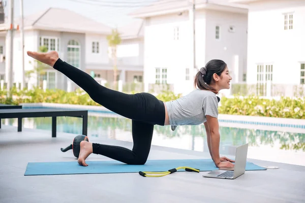 Mutlu Asyalı kadın, sabahları evde egzersiz ve yoga yapıyor. 