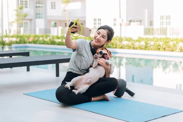 Mutlu Asyalı kadın köpeğiyle selfie çekiyor. 