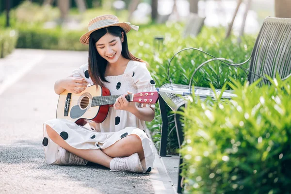 Parkta gitar çalan Asyalı kadın etkiler içerik, yaşam tarzı ve dinlenme konsepti oluşturmak için.