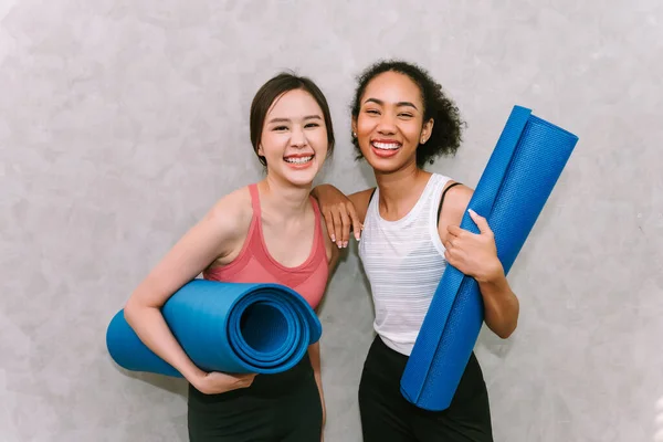 Young adult women carring yoga mat ,smiling and happy emotion , exercising at home with friends , sport and recreation concept.