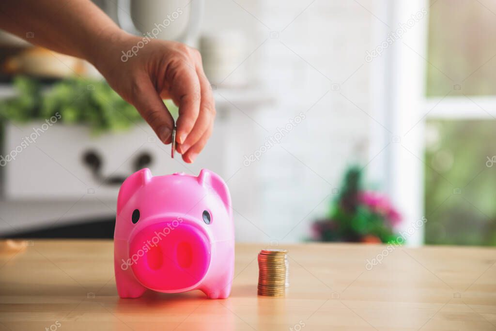 Hand putting coints into piggy bank saving money and money planning, financial concept