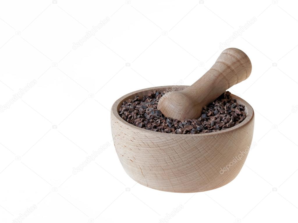 Cacao nibs in pestle isolated on white