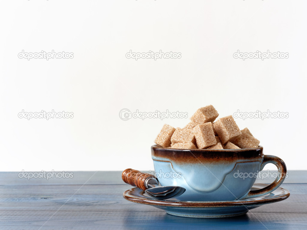 Brown sugar cubes in cup on wood