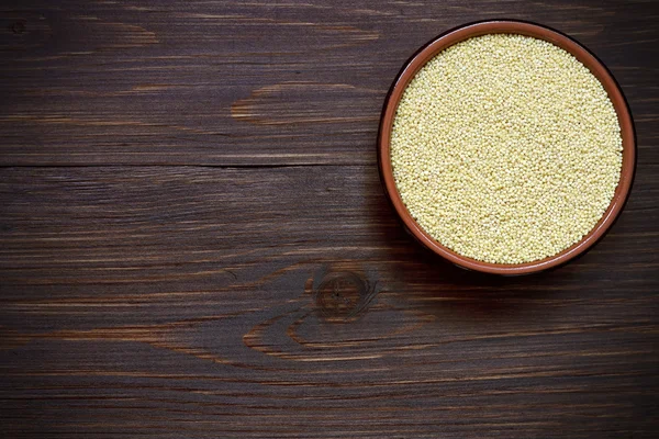 Organic millet in a bowl on wood — Stock Photo, Image