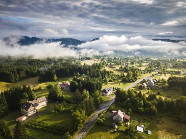 Güneşin sisle aydınlattığı yaz fırtınasından sonra Jesenak köyünün çevresindeki sabah manzarası.
