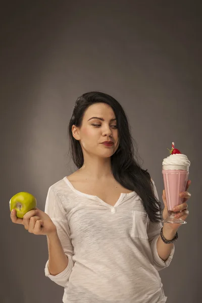 girl with apple and milkshake trying to decide which to have