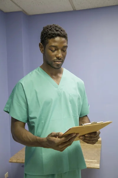 African american doctor reads medical charts — Stock Photo, Image