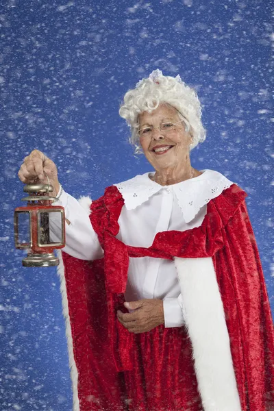 在雪地里拿着一盏灯笼的夫人圣诞老人 图库图片