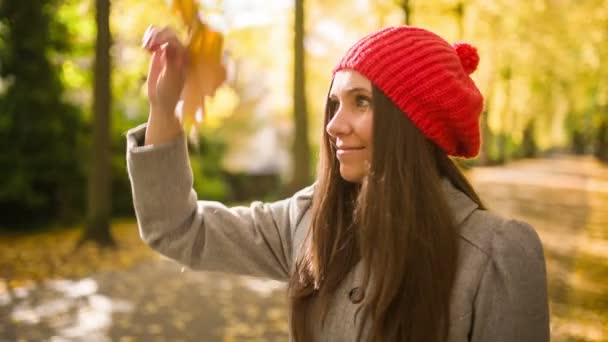 Jonge vrouw met blad in park spelen — Stockvideo