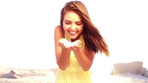 Девушка выдувает песок из рук — стоковое видео