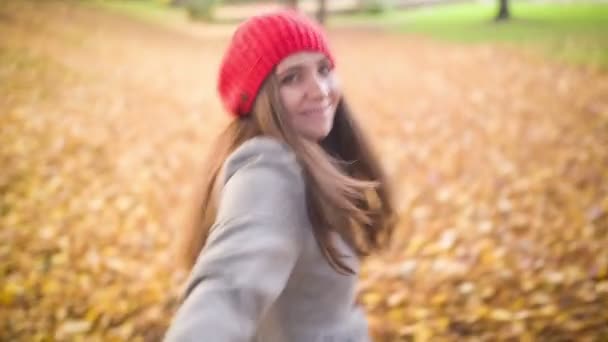 Ung kvinna dra sin pojkvän genom hösten park — Stockvideo