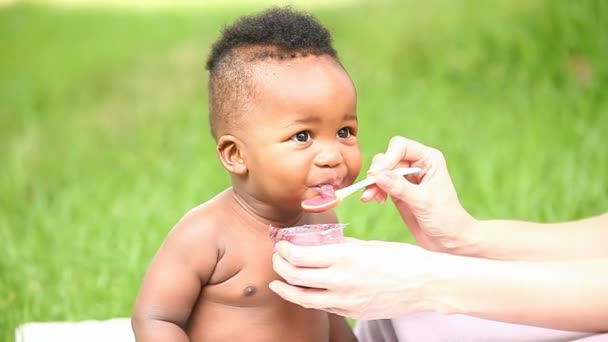 Ребенок улыбается, пока его кормит мать. — стоковое видео