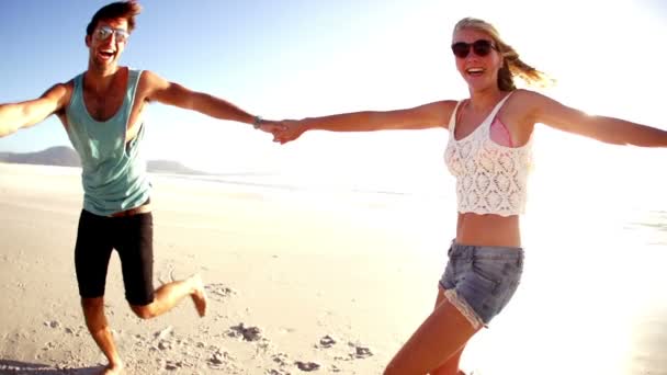 Друзі крутяться тримаючи пляж рук — стокове відео