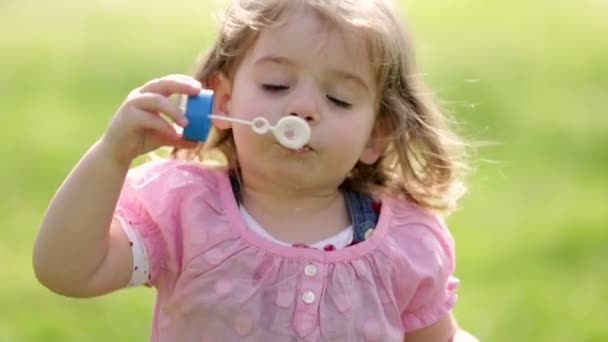 Little girl having fun blowing soap bubble — Stock Video