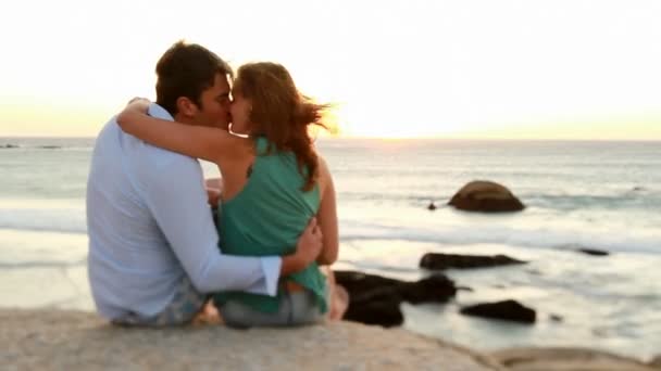 Couple in love is sitting on a rock near the sea — Stock Video