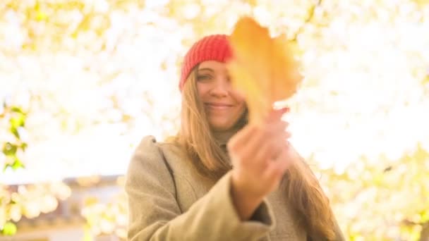 Женщина играет с осенним листом и опадающими листьями — стоковое видео