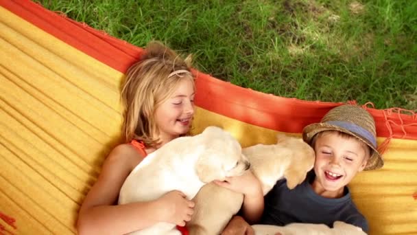 Діти з цуценятами лежать в гамаку — стокове відео