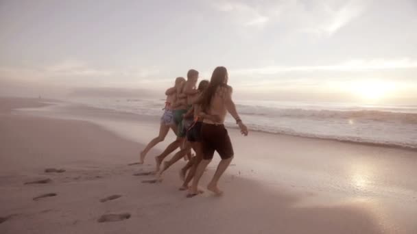 Amigos corriendo al agua en la playa — Vídeo de stock