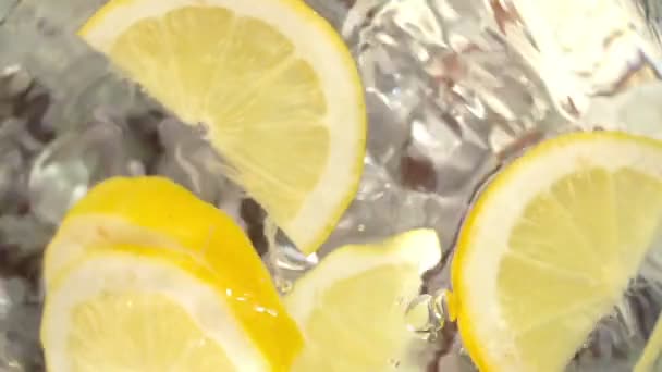 Ice cubes and lemon slices falling into jug of water — Stock Video