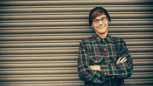 Sonriente hombre hipster apoyado en la puerta de metal — Vídeos de Stock