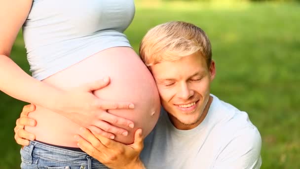 Father listening on his pregnant wife's baby belly — Stock Video