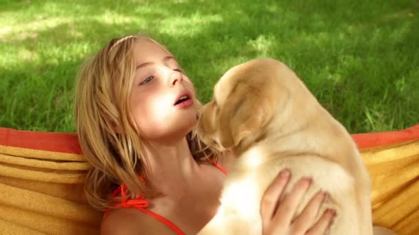 Happy girl holding labrador puppies while swinging in hammock — Stock Video