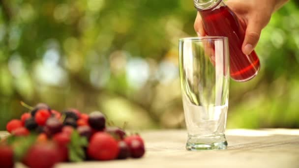 Eine Person gießt Beerensaft ins Glas — Stockvideo