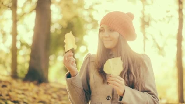 Ung kvinna leker med blad i park — Stockvideo