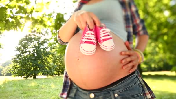 Mujer embarazada sosteniendo zapatos de bebé rosados — Vídeos de Stock