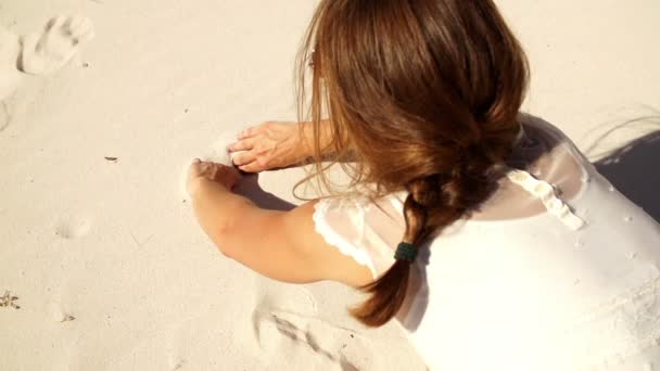 Girl is painting a heart into the sand — Stock Video