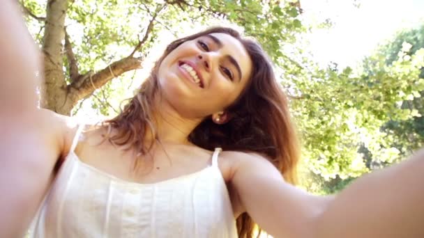 Young woman taking a selfie in the park — Stock Video