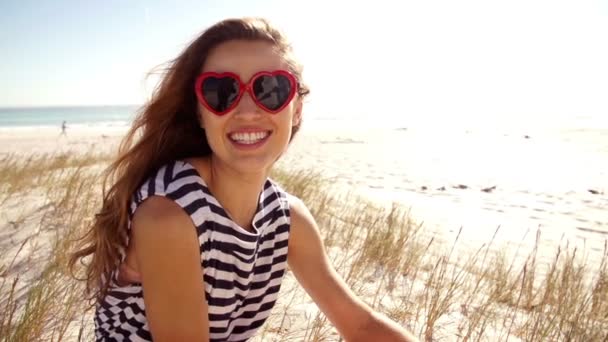 Chica sonriendo con gafas de sol en forma de corazón — Vídeos de Stock