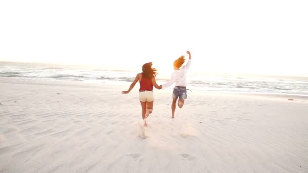 Beste vrienden springen langs het strand — Stockvideo