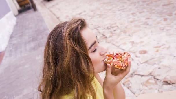 Mulher comendo uma pizza sentada na rua — Vídeo de Stock