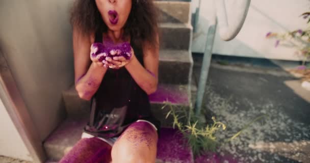 Tenåringsjente Afroamerikansk Jente Med Hipsterhette Sittende Fortau Blåsende Rosa Glitter – stockvideo
