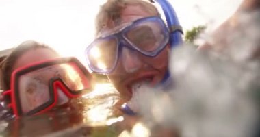 Düşük açılı çift birlikte Şnorkelle Dalma dişli güneş ve lens flare ile bir yaz akşamı giyen bir havuzda gülüyor vurdu