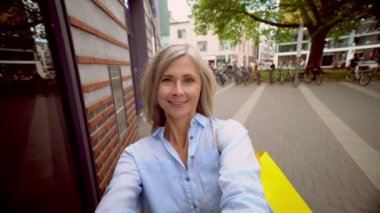 Gülümseyen bir selfie alarak bir şehir sokakta zarif gri saçlı Olgun kadın