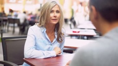 Olgun kadının şehirde bir arkadaşıyla açık bir kafede kahve bir fincan gülümseyen